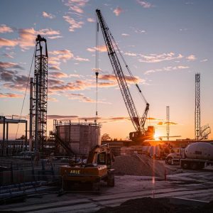 a bustling construction site showcases an on-site fueling service in action, with bright machinery refueling efficiently beside a towering crane, emphasizing the streamlined operation and cost-saving benefits for construction companies.